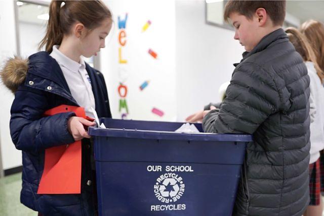 Girl and boy student holding recycling can